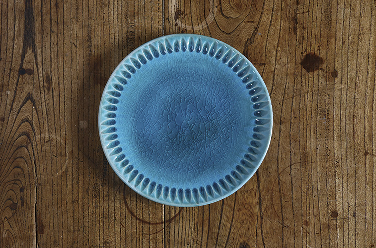 多彩な用途に対応する鎬平皿。写真のトルコ青は、焼きあがり時のひび割れ模様や色のつき具合がひとつ ひとつ異なる。作っては売れるという人気商品。5,940円