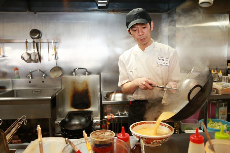 鍋をふるう店長の会田さん