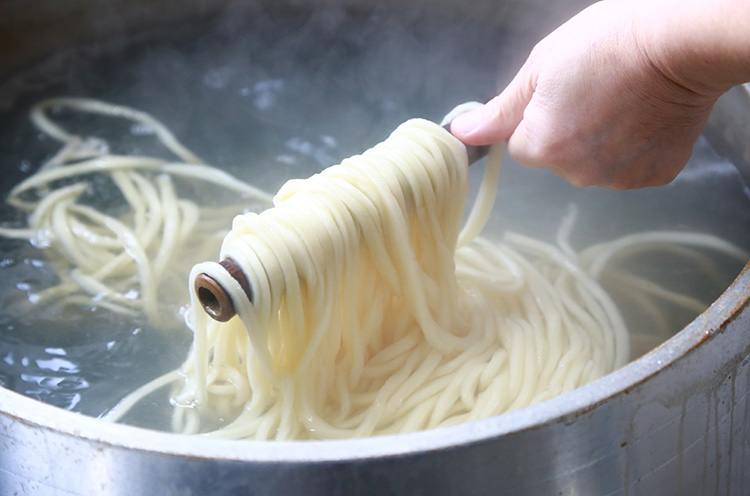 釜で約15分間じっくりとゆでる。竹で麺をかき混ぜるのは高野さん流