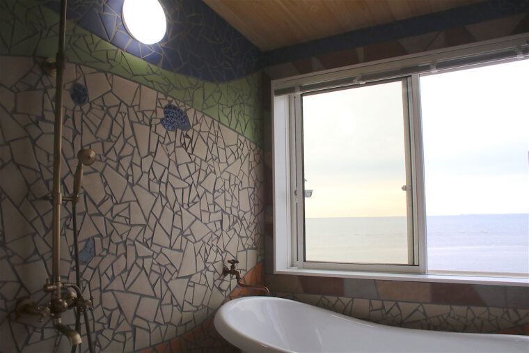「夕日の間」の浴室の壁のモザイクタイルは波をイメージしたデザ インに