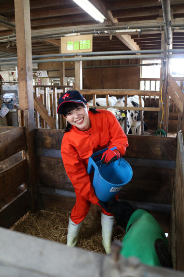 子牛にミルクをあげるべく奮闘中。大変なはずなのにいい笑顔！