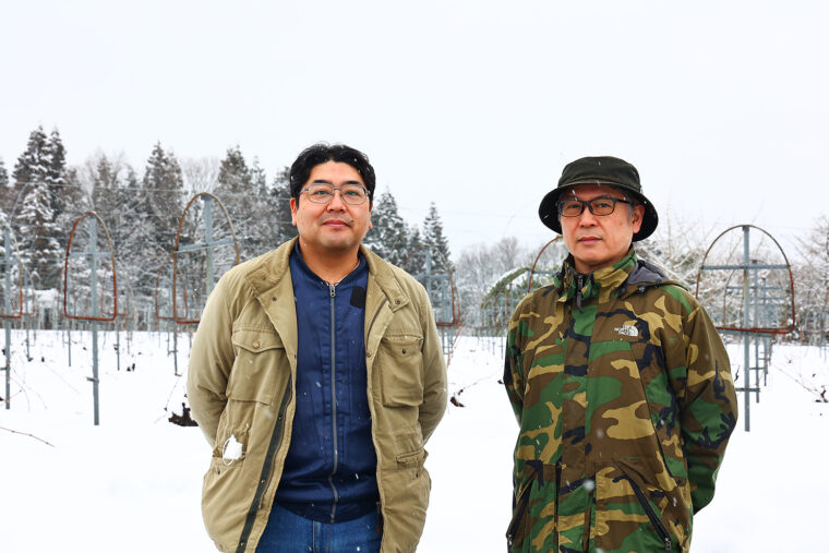 生産者の馬場弘次さん（左）と、販売担当の大竹幸輔さんをブドウ畑で。撮影時はまだ雪に覆われていました