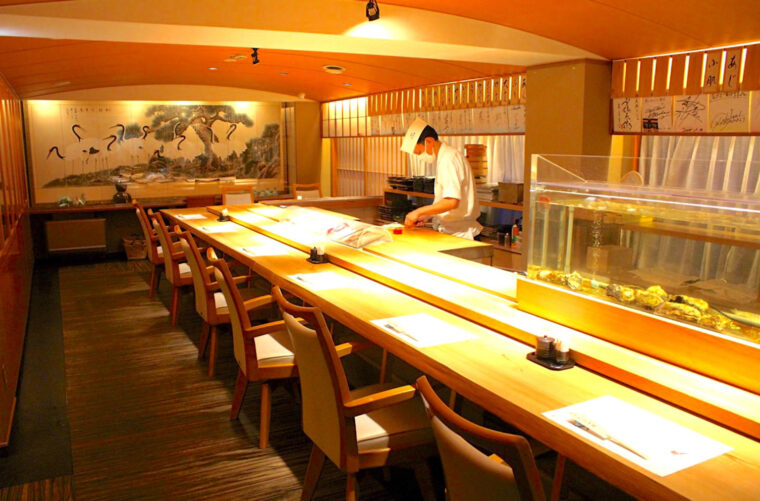 大きな一枚板のカウンターと風情を感じる日本画の室内。座敷やテーブル席もある