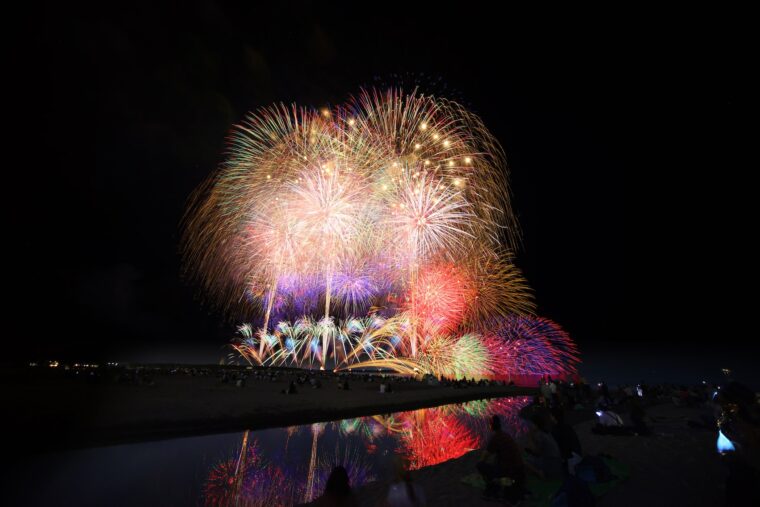 海面に映る花火の美しさと迫力を砂浜に座って味わおう