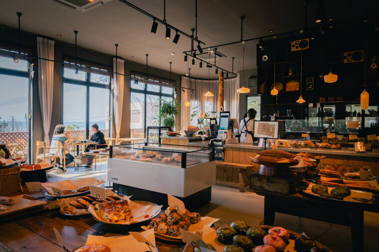COBO BAKERY SHOP店内。海や松林といった自然豊かな立地に加えて、注目すべきはハード系をはじめとした 旬の素材をいかした個性派パンとラグジュアリーな雰囲気。 テラス席でドリンクを片手に好みのパンを味わうのもおすすめ