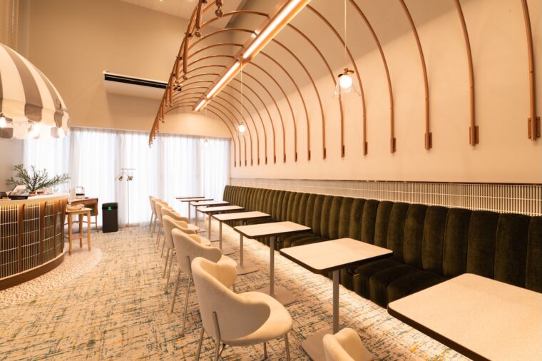 高い天井とアーチ状の飾りが特徴。モスグリーンのベンチソファが落ち着いた雰囲気を演出します