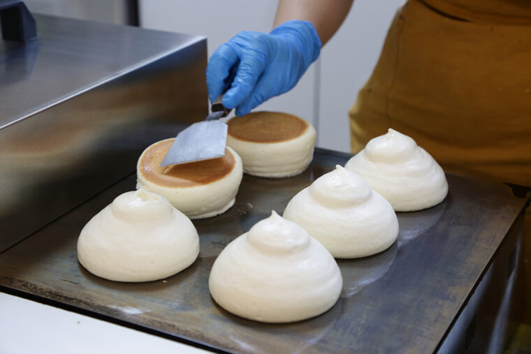 熟練の手つきでふわふわの生地をきれいにひっくり返します