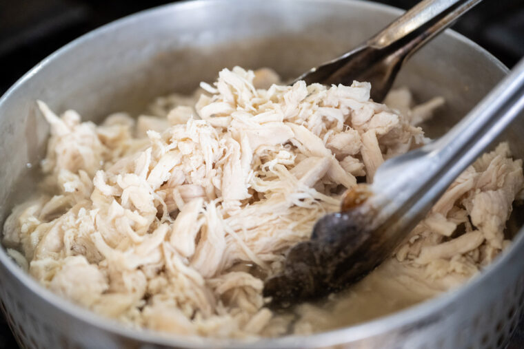 タレがしっかりと染み込むよう細かく裂かれた蒸し鶏