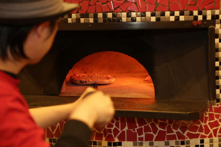 移転前から使用している薪石窯でピザを焼き上げる深井さん