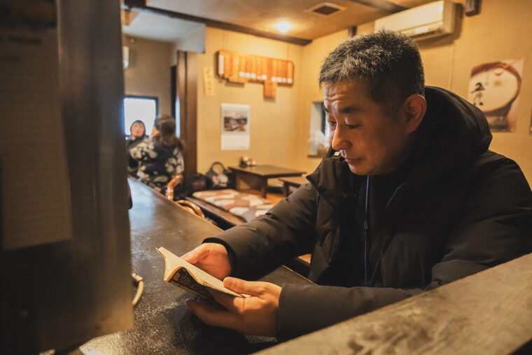 読書をして料理を待つ小倉さん