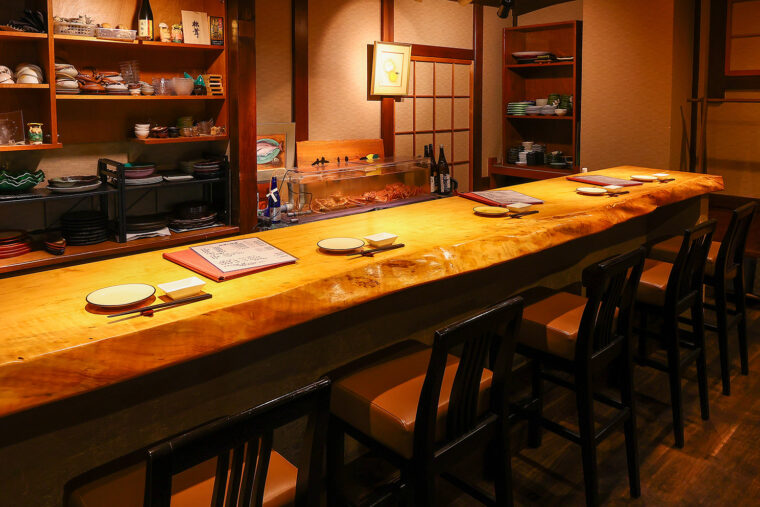 大きな一枚板でできたカウンター席では、店主との会話も楽しめる