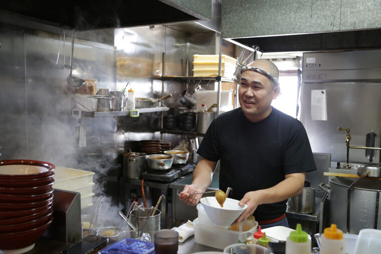 アルビ好きの店主・藤野尚志さん。店内にはユニホームがズラリ
