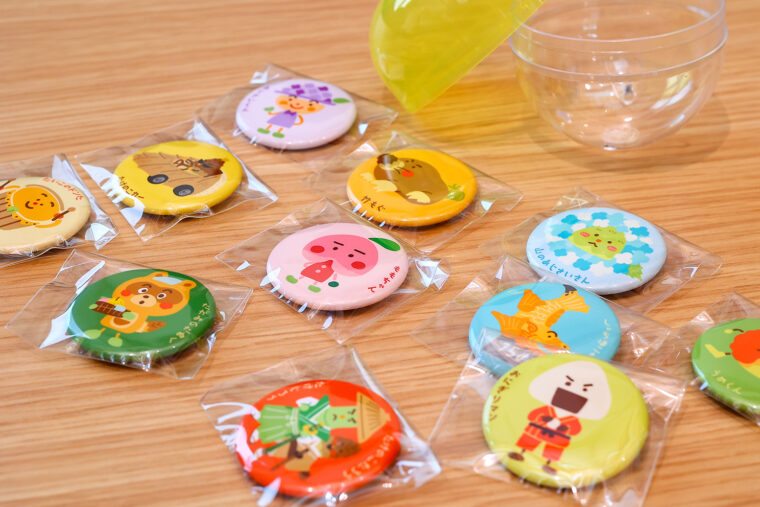 羽生田小学校の生徒が考案したカプセルトイ（1回200 円）。全11種類のオリジナル缶バッジが当たる！